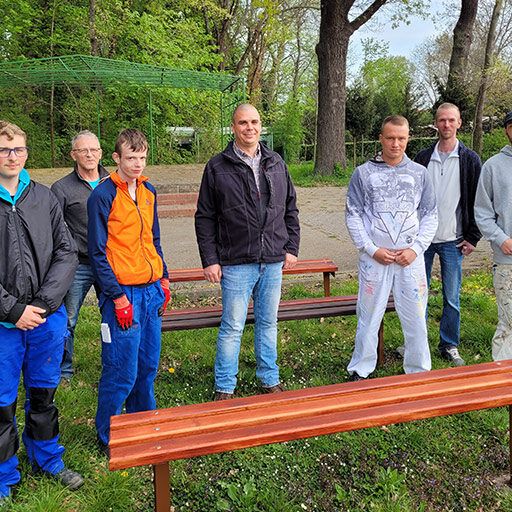 Gruppe von Auszubildenden mit Ausbildern vor hinter einer neu aufgestellten Parkbank