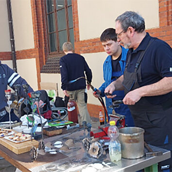 Die Auszubildenden der Metallabteilung stellen eiserne Rosen auf dem Schulhof her