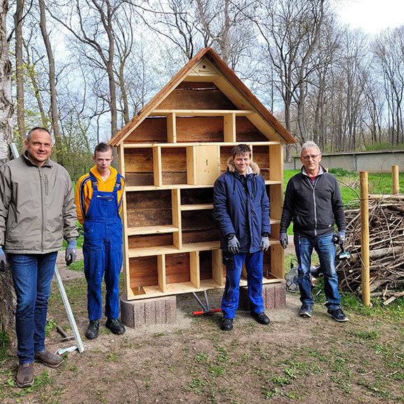 Jugendliche aus der Berufsvorbereitung und Mitarbeiter vor einem fertiggestellten Insektenhotel