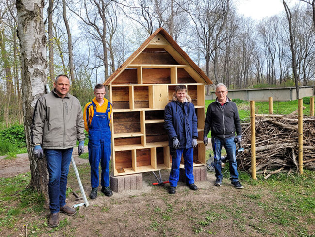Jugendliche aus der Berufsvorbereitung und Mitarbeiter vor einem fertiggestellten Insektenhotel