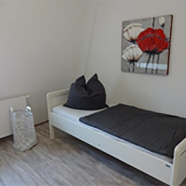 Bild eines aufgeräumten Zimmers mit einem Bett in der Ecke