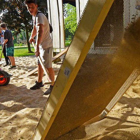 Teilnehmergruppe beim Durchsieben des Spielsandes