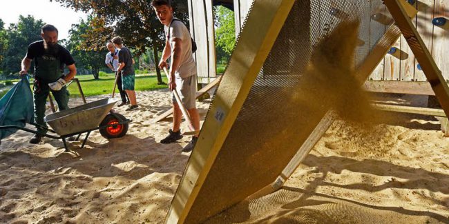 Teilnehmergruppe beim Durchsieben des Spielsandes