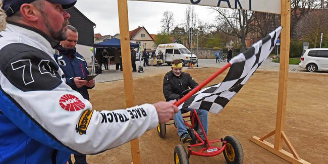 Junge fährt mit einem Tretauto durchs Ziel