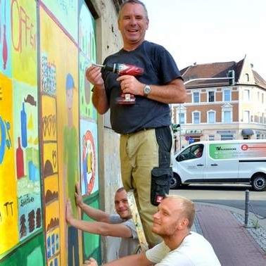 Tino Hartmann mit Bohrmaschine in der Hand beim aufhängen von Bildern